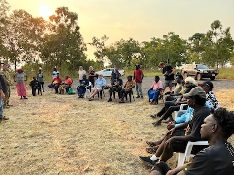 Crowd sitting in chairs in a circle talking 
