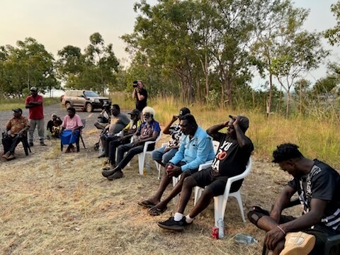 Crowd sitting in chairs in a circle talking in Wadeye 
