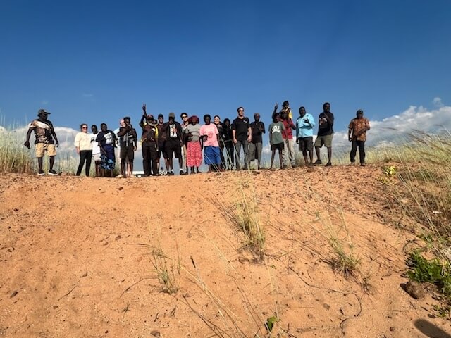 Aboriginal Traditional Owners standing in a straight line on a sand dune in Wadeye 