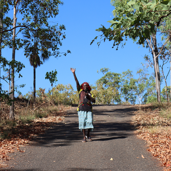 Woman standing on a road waving goodbye